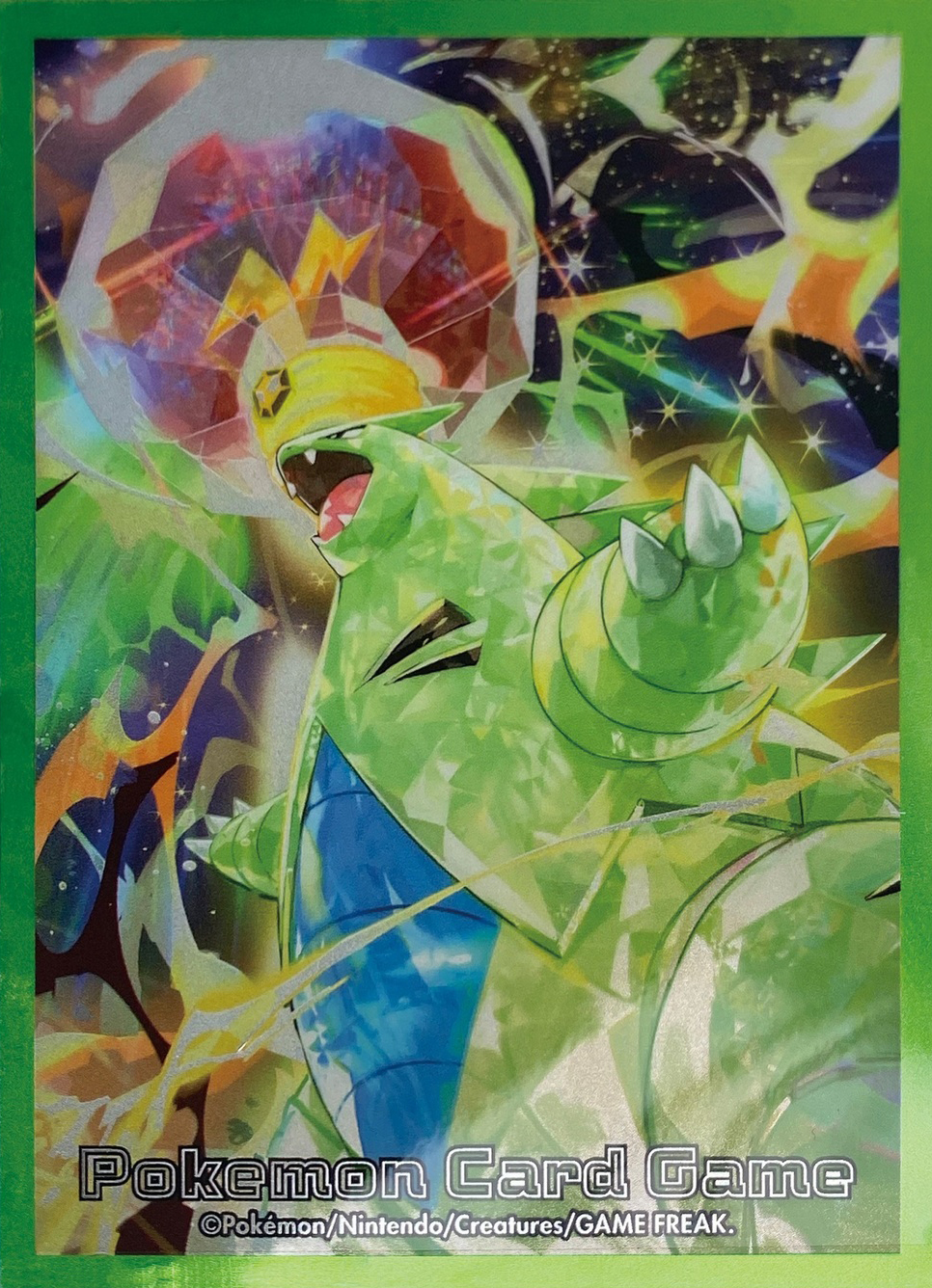 border claws company_name copyright_name copyright_notice electricity fangs gen_2_pokemon green_border highres nejita nintendo no_humans official_art open_mouth pokemon pokemon_(creature) pokemon_focus pokemon_tcg solo terastallization third-party_source tyranitar v-shaped_eyes