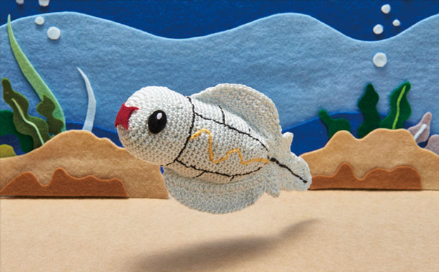 amigurumi_(medium) animal_focus asako_ito black_eyes commentary creature english_commentary fish from_side gen_5_pokemon nature nintendo official_art outdoors photo_(medium) pokemon pokemon_(creature) pokemon_tcg profile seaweed solo third-party_source tynamo unconventional_media underwater water
