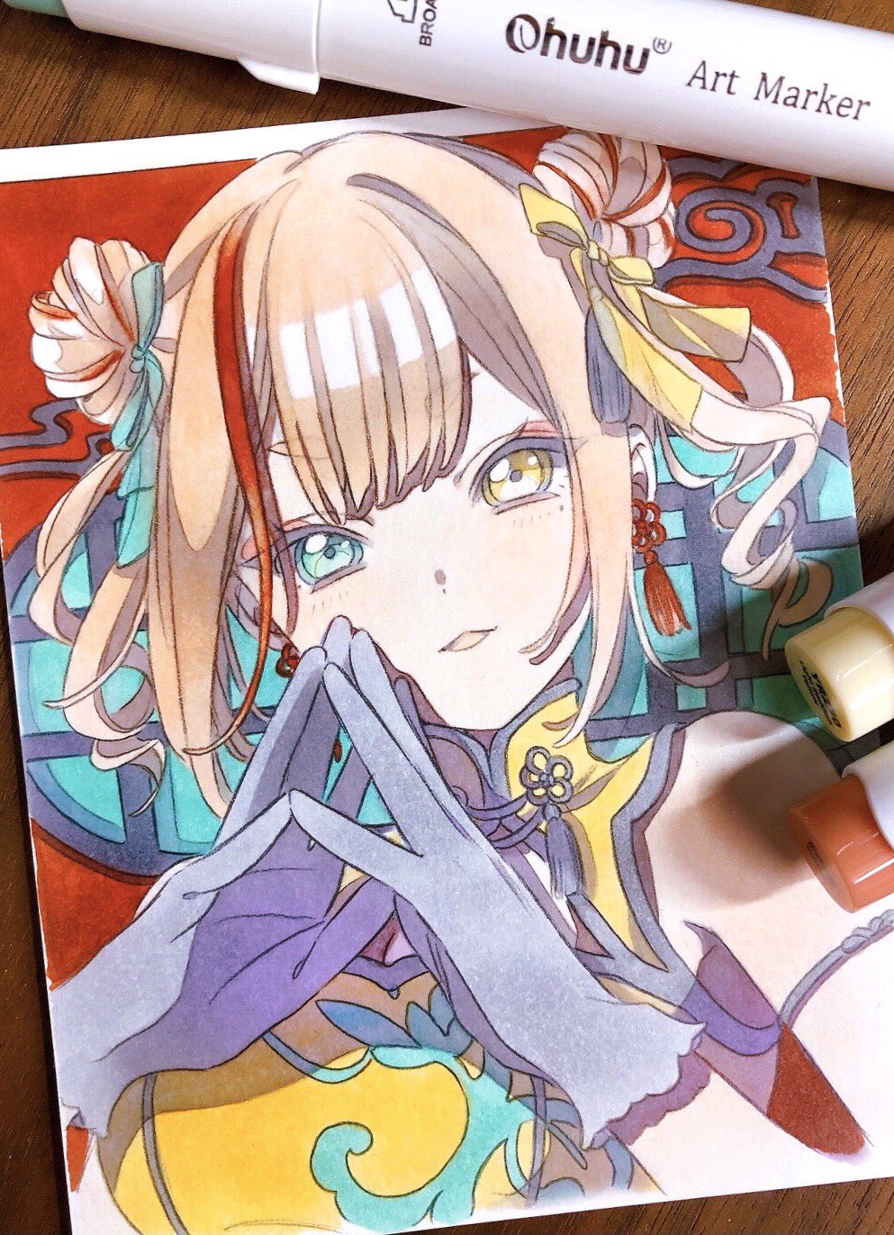 1girl :3 art_tools_in_frame bare_shoulders blue_eyes blue_gloves blue_ribbon blush brown_hair china_dress chinese_clothes double_bun dress earrings english_text gloves graphite_(medium) hair_bun hair_ribbon heterochromia highres jewelry lattice looking_at_viewer marker marker_(medium) multicolored_hair original parted_lips pato_(ptro) red_background red_hair ribbon solo sponsor steepled_fingers streaked_hair tassel tassel_earrings traditional_media twintails upper_body yellow_dress yellow_eyes yellow_ribbon