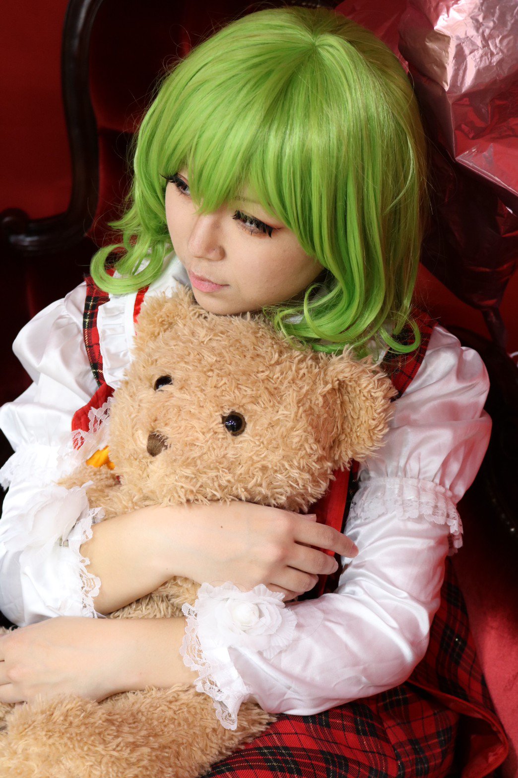 1girl ascot balloon black_eyes chair commentary_request cosplay cosplay_photo eyelashes female_focus frilled_shirt_collar frills green_hair hair_between_eyes highres holding holding_stuffed_toy hugging_object juliet_sleeves kazami_yuuka kazami_yuuka_(cosplay) long_sleeves photo_(medium) plaid_clothes plaid_skirt plaid_vest puffy_sleeves red_skirt red_vest shirt skirt skirt_set smile solo stuffed_animal stuffed_toy teddy_bear touhou upper_body vest white_shirt yellow_ascot