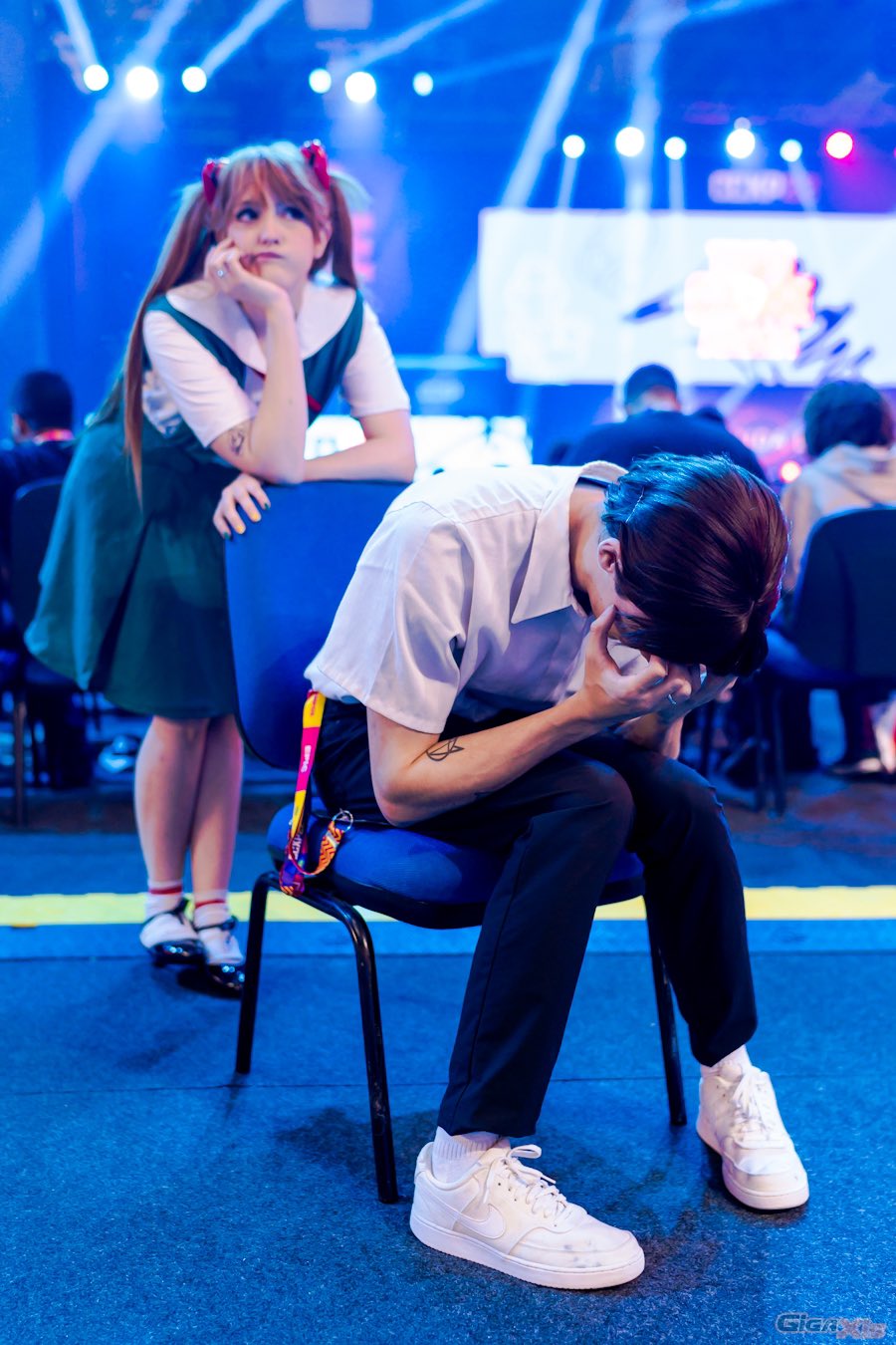 1boy 1girl 6+others arm_support brazilian_(nationality) brown_hair chair cosplay depressed full_body hairpods highres ikari_shinji ikari_shinji_(cosplay) interface_headset_(evangelion) looking_to_the_side meme memepantazis multiple_others neon_genesis_evangelion photo_(medium) school_uniform shinji_in_a_chair_(meme) short_hair sitting souryuu_asuka_langley souryuu_asuka_langley_(cosplay) tokyo-3_middle_school_uniform twintails twitter_username two_side_up
