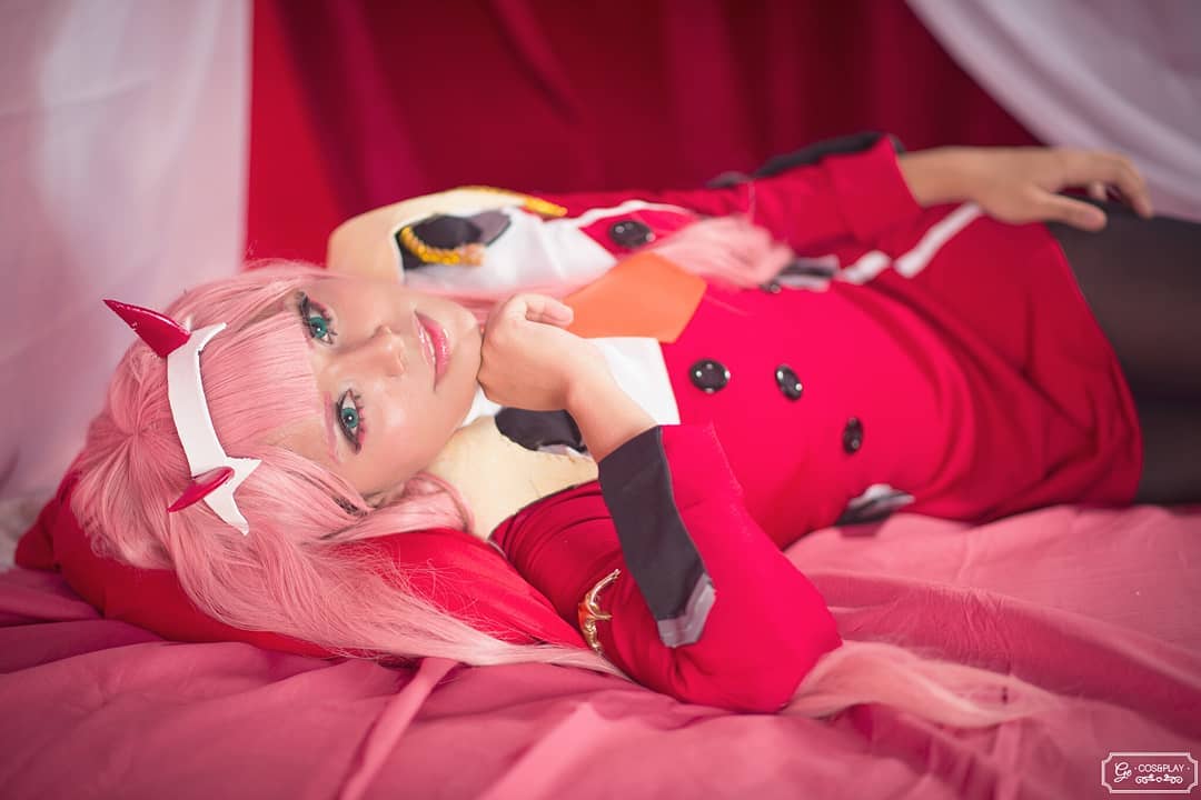1girl blue_eyes cosplay curtains darling_in_the_franxx geisi long_hair looking_at_viewer pillow pink_hair solo solo_focus zero_two_(darling_in_the_franxx)