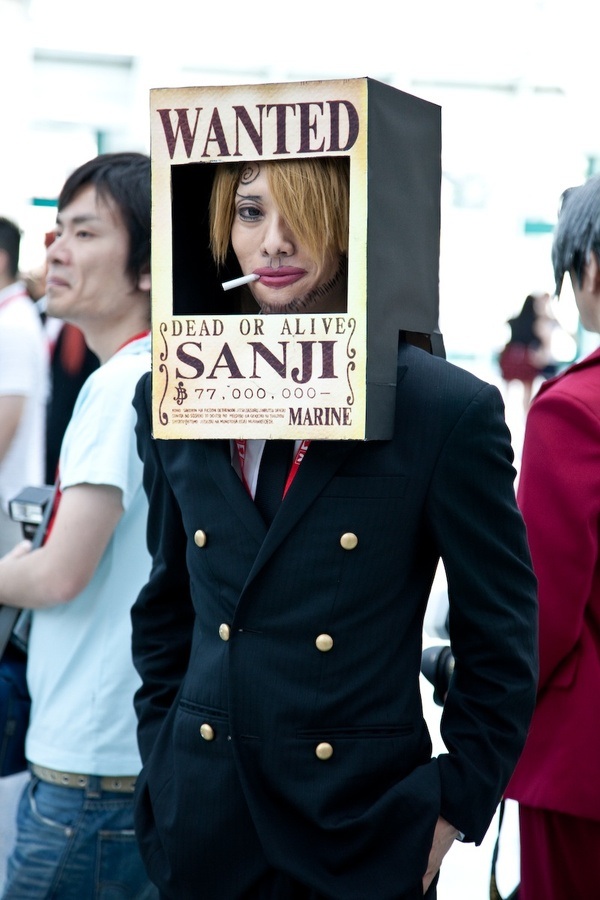 ace_attorney blonde_hair capcom character_name cosplay formal_clothes hands_in_pockets looking_at_viewer male_focus miles_edgeworth one_piece photo_(medium) poster sanji_(one_piece) sanji_(one_piece)_(cosplay) suit wanted_poster
