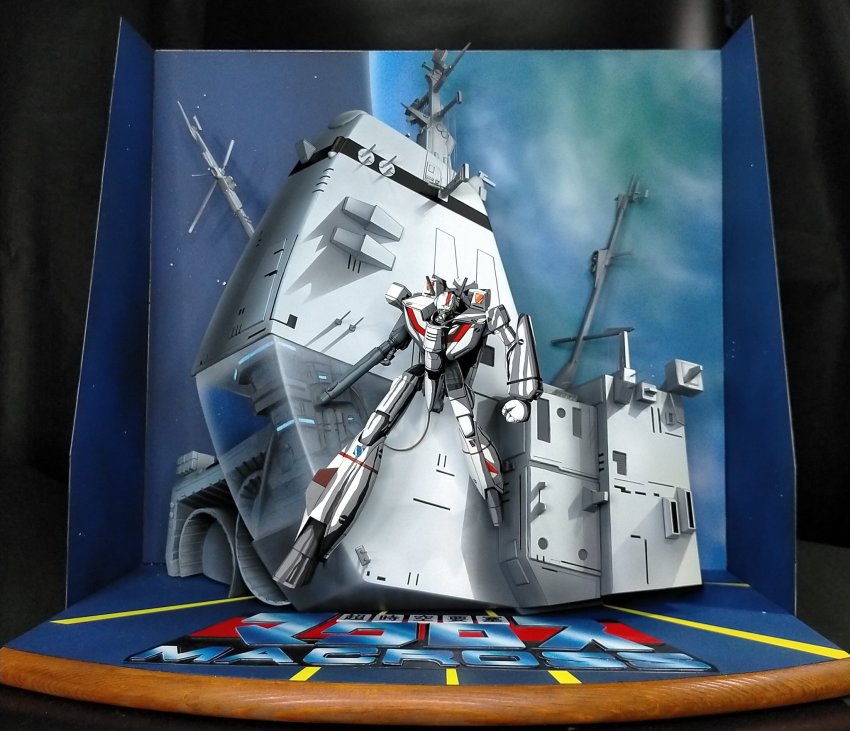 annkoromoti choujikuu_yousai_macross clenched_hands copyright_name diorama diorama_(medium) gun highres holding holding_gun holding_weapon logo looking_down macross mecha model_kit model_kit_(medium) no_humans photo_(medium) robot science_fiction sdf-1 solo unconventional_media vf-1j visor weapon