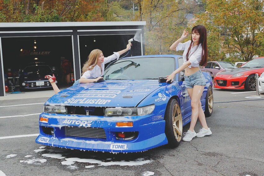 2girls asian blonde_hair blue_car blue_shorts brown_hair car cosplay_photo denim denim_shorts grey_footwear high_heels initial_d leaning_forward leaning_to_the_side mayamelo5 mazda mazda_rx-8 midriff motor_vehicle multiple_girls navel nissan nissan_180sx nissan_sileighty nissan_silvia nissan_silvia_s13 parted_lips photo_(medium) red_car red_footwear red_lips satou_mako sayuki_(initial_d) shoes shorts smile sneakers soap tree vehicle_focus washing_vehicle yuki_(bigbong)