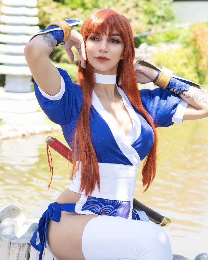 1girl breasts brown_hair cleavage cosplay dead_or_alive highres kasumi_(doa) kasumi_(doa)_(cosplay) large_breasts long_hair photo_(medium) real_life rociomadariagaa short_sleeves sitting solo sword tattoo thighhighs water weapon