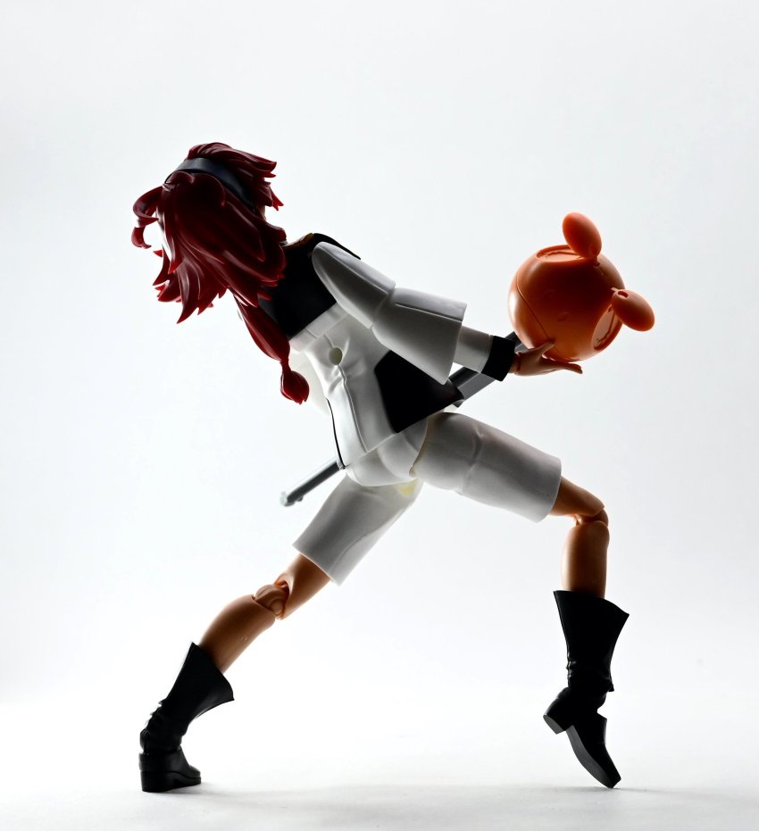 1girl boots cosplay doll_joints freddie_mercury freddie_mercury_(cosplay) from_behind gundam gundam_suisei_no_majo hairband haro highres holding holding_microphone itashanxd joints low_ponytail microphone model_kit_(medium) name_connection photo_(medium) ponytail red_hair school_uniform shorts solo suletta_mercury unconventional_media