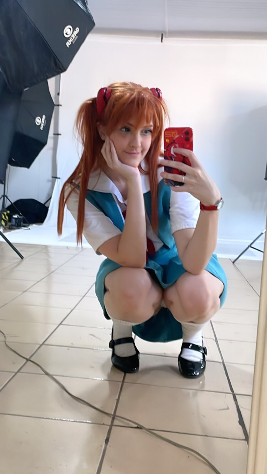 1girl arm_tattoo blue_eyes brazilian_(nationality) brown_hair cosplay full_body hairpods highres holding holding_phone interface_headset_(evangelion) lips looking_at_viewer memepantazis neon_genesis_evangelion panties phone photo_(medium) school_uniform selfie skirt smile souryuu_asuka_langley souryuu_asuka_langley_(cosplay) squatting standing suspender_skirt suspenders tattoo tokyo-3_middle_school_uniform twintails two_side_up underwear white_panties