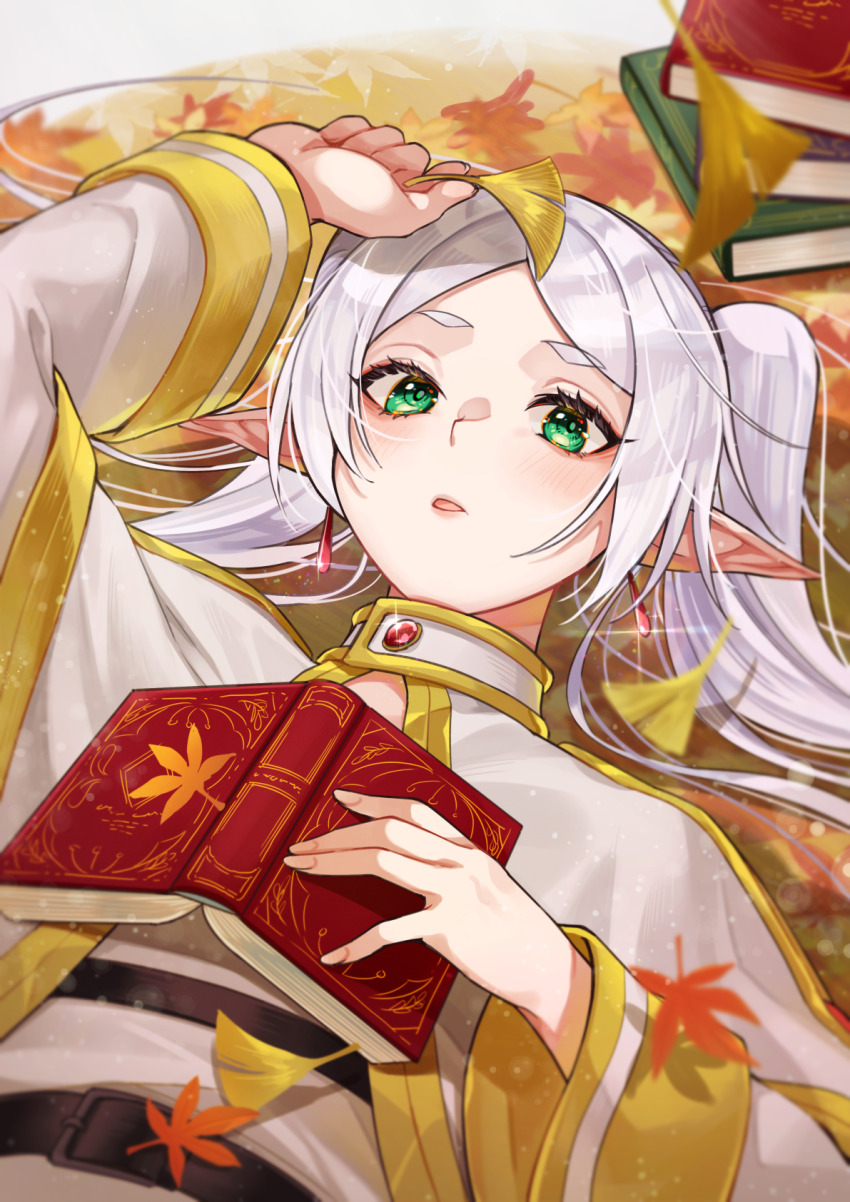 1girl arm_up autumn_leaves blush book book_stack capelet earrings elf frieren ginkgo_leaf glint green_eyes grey_hair highres holding holding_book holding_leaf ichino_tomizuki jewelry leaf long_hair long_sleeves looking_at_viewer lying on_back open_book parted_bangs parted_lips pointy_ears solo sousou_no_frieren twintails upper_body white_capelet