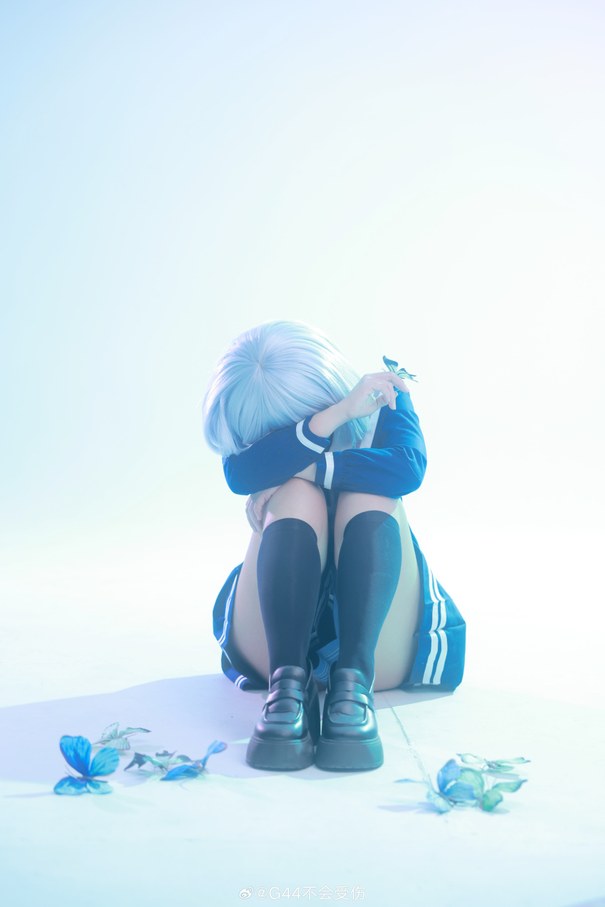 1girl absurdres arms_on_knees artist_name bang_dream! black_shoes black_socks bloom blue_butterfly blue_skirt bug butterfly butterfly_on_hand chinese_commentary commentary_request cosplay_photo covered_eyes full_body green_butterfly highres hugging_own_legs insect jisi_si kneehighs knees_to_chest kurata_mashiro loafers long_hair on_floor photo_(medium) pleated_skirt school_uniform shoes short_hair sidelighting simple_background sitting skirt socks solo tsukinomori_school_uniform very_long_hair watermark weibo_watermark white_background white_hair winter_uniform