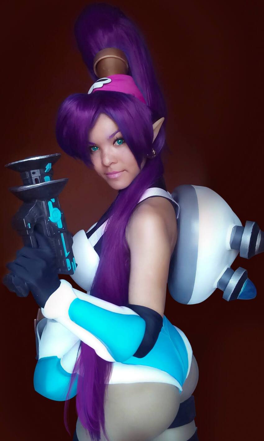 1girl ass backpack bag bare_shoulders breasts cosplay cosplay_photo dark-skinned_female dark_skin earrings elbow_gloves from_side gloves green_eyes gun headband highres jewelry large_breasts leotard leslie_salas long_hair mighty_switch_force! patricia_wagon patricia_wagon_(cosplay) photo_(medium) pointy_ears purple_hair real_life shantae shantae_(cosplay) shantae_(series) shantae_and_the_pirate&#039;s_curse thong_leotard very_long_hair weapon