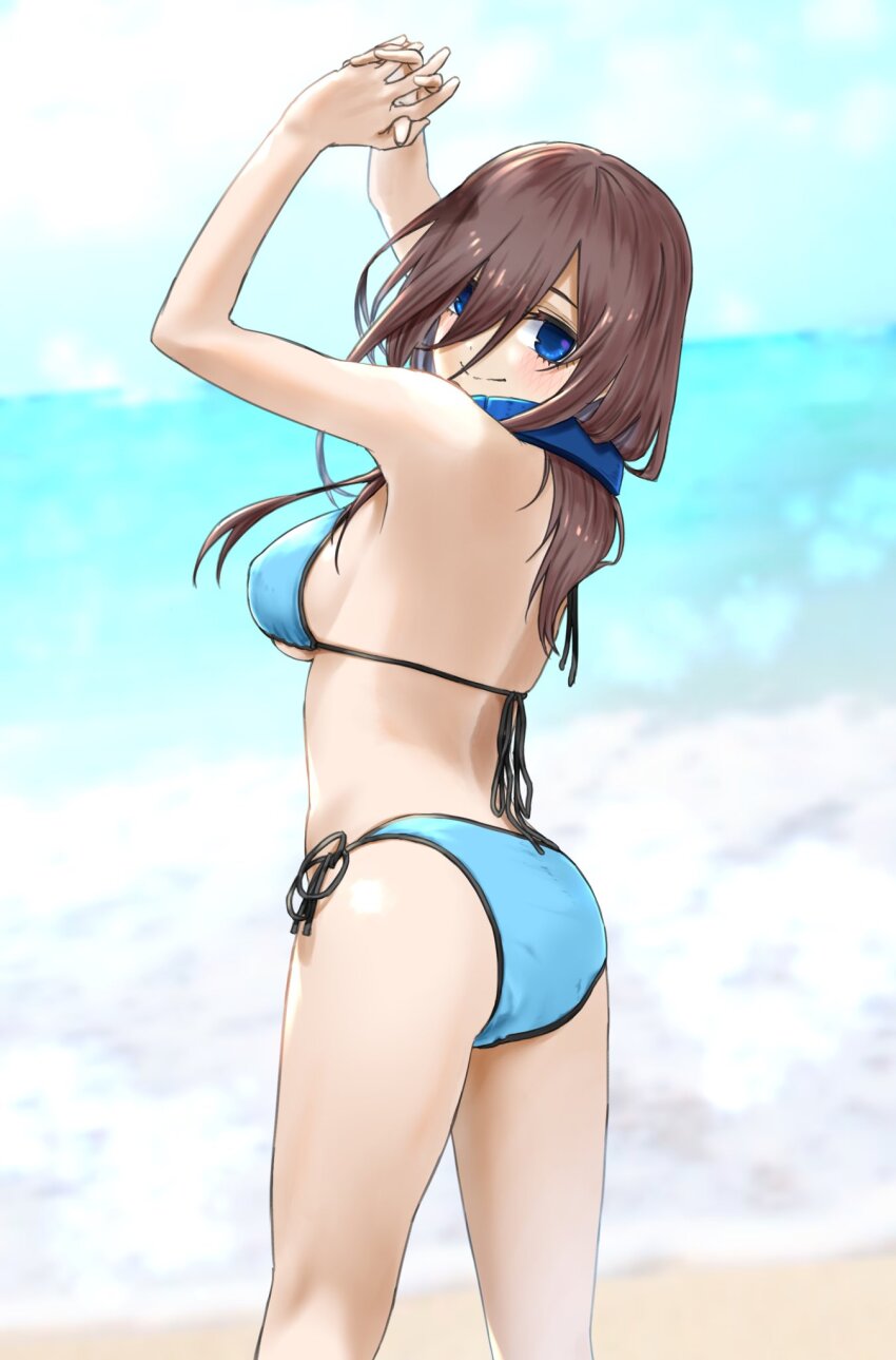 1girl arms_up ass back beach bikini blue_bikini blue_eyes blush breasts brown_hair closed_mouth commentary_request day from_behind go-toubun_no_hanayome hair_between_eyes halterneck headphones headphones_around_neck highres horizon interlocked_fingers long_hair long_hair_between_eyes looking_at_viewer looking_back medium_breasts mitsugu nakano_miku ocean outdoors own_hands_clasped own_hands_together shore side-tie_bikini_bottom sky solo standing string_bikini swimsuit