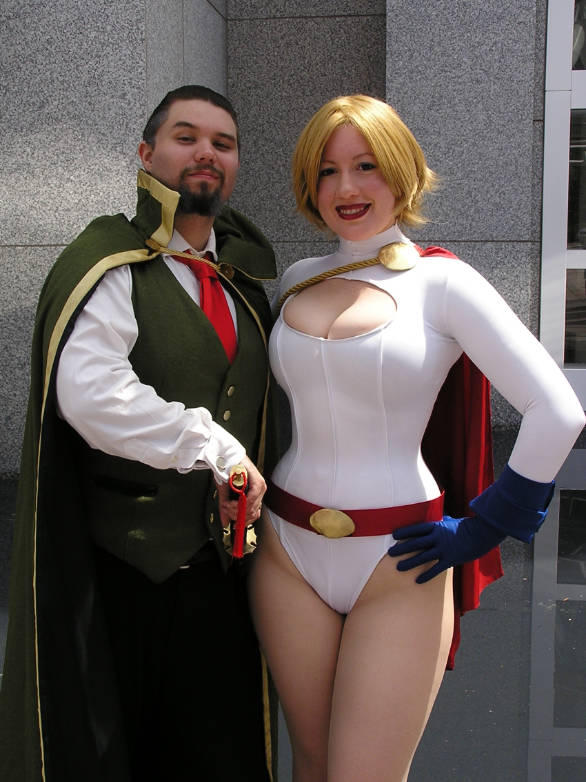 1boy 1girl belt blonde_hair breasts cape cleavage cleavage_cutout clothing_cutout cosplay dc_comics gloves highres leotard photo_(medium) power_girl power_girl_(cosplay)