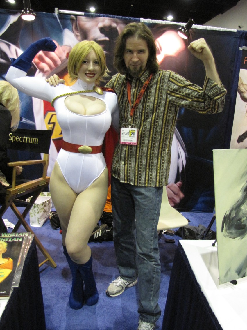 1boy 1girl absurdres belt blonde_hair breasts cape cleavage cleavage_cutout clothing_cutout cosplay dc_comics gloves highres leotard photo_(medium) power_girl power_girl_(cosplay)