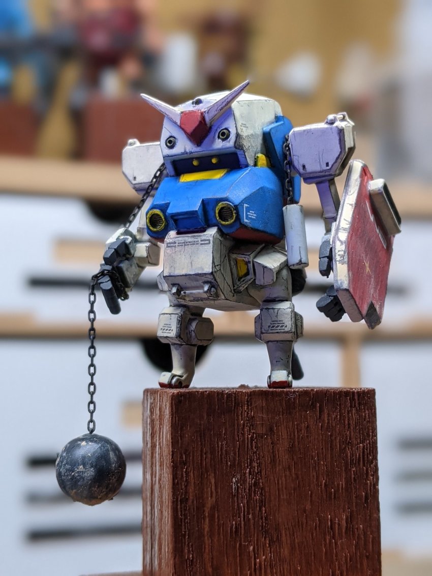 ball_and_chain_(weapon) blurry blurry_background cavico_models fusion gundam highres jgsdf_type_07_tank_nacchin looking_ahead matage_sanjuro mecha mobile_suit_gundam model_kit model_kit_(medium) no_humans open_hands photo_(medium) robot rx-78-2_gundam shield unconventional_media v-fin yellow_eyes