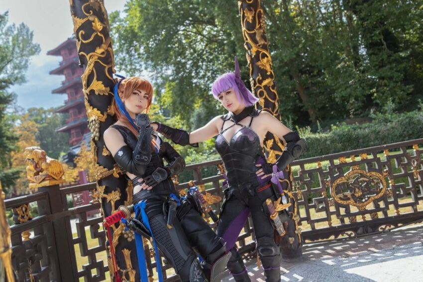 2girls ayane_(doa) ayane_(doa)_(cosplay) azelyah bare_shoulders belgian_(nationality) blue_eyes bodysuit breasts brown_hair cloud cosplay dead_or_alive fingerless_gloves gloves hand_on_own_hip kasumi_(doa) kasumi_(doa)_(cosplay) large_breasts long_hair multiple_girls ninja_gaiden photo_(medium) ponytail purple_hair real_life short_hair tree zarkaline