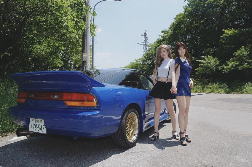 2girls asian black_footwear black_skirt blonde_hair blue_car brown_hair car cloud cosplay_photo hand_on_own_hip high_heels holding_hands initial_d license_plate long_hair looking_at_viewer mayamelo5 midriff_peek motor_vehicle multiple_girls navel nissan nissan_180sx photo_(medium) satou_mako sayuki_(initial_d) shadow skirt sky smile sports_car suspenders tree yuki_(bigbong)