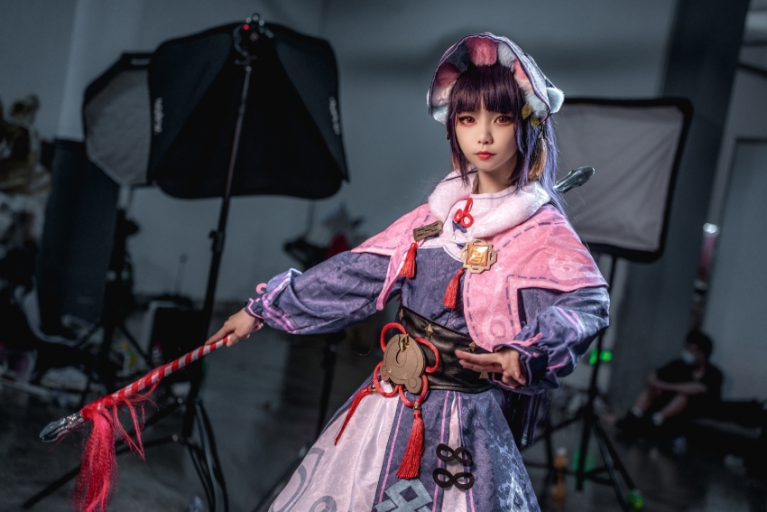 1girl chinese_clothes cosplay cosplay_photo highres holding holding_weapon indoors looking_at_viewer photo_(medium) photo_background purple_hair realistic weapon yun_jin_(genshin_impact) yun_jin_(genshin_impact)_(cosplay)