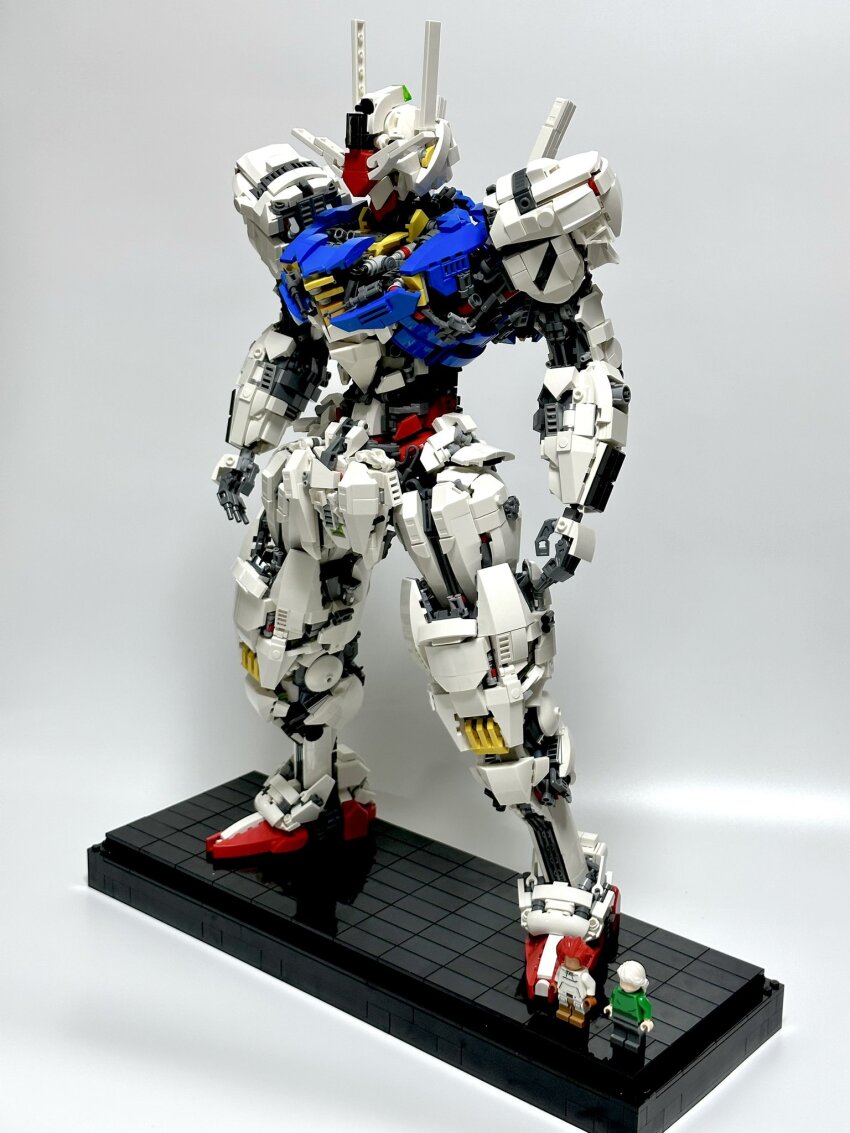 2girls black_pants faceless faceless_female green_sweater gundam gundam_aerial gundam_suisei_no_majo highres lego_(medium) lego_minifig mecha mecha_focus miorine_rembran mobile_suit multiple_girls pants pilot_suit red_hair robot science_fiction seirei_(seirei526) shadow standing suletta_mercury sweater unconventional_media v-fin white_hair