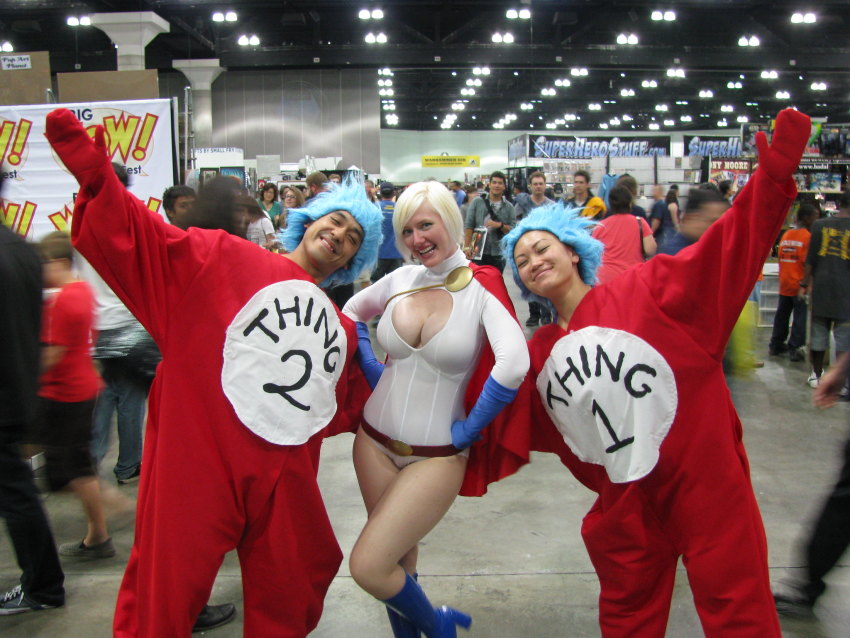 1girl 2boys belt blonde_hair breasts cape cleavage cleavage_cutout clothing_cutout cosplay dc_comics gloves highres leotard multiple_boys photo_(medium) power_girl power_girl_(cosplay) superman_(series) the_cat_in_the_hat thing_1 thing_2