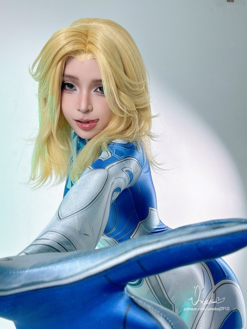 1girl artist_name blonde_hair blue_bodysuit bodysuit cosplay cosplay_photo fantastic_four female_focus highres licking_lips looking_at_viewer marvel marvel_rivals multicolored_bodysuit photo_(medium) real_life solo sue_storm sue_storm_(cosplay) superhero_costume tongue tongue_out two-tone_bodysuit umeko_j umekojcosplayer watermark white_bodysuit