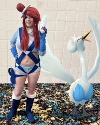 1girl beak bird boots breasts cosplay cosplay_photo crop_top gen_5_pokemon gloves goosaphone hand_on_own_hip highres large_breasts long_hair long_sleeves looking_at_viewer nintendo photo_(medium) poke_ball pokemon pokemon_bw real_life red_hair shorts skyla_(pokemon) skyla_(pokemon)_(cosplay) swanna thigh_strap wings