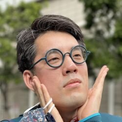  1boy albert_yi aqua-framed_eyewear asian black_hair blurry blurry_background closed_mouth danbooru_(site) day glasses hands_on_own_face hands_up highres holding holding_mask male_focus mask outdoors photo_(medium) portrait real_life round_eyewear short_hair solo unworn_mask 