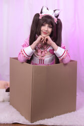  1girl absurdres animal_ears bell bow box brown_eyes brown_hair buttons cardboard_box cat_ears cat_girl chocola_(nekopara) chocola_(nekopara)_(cosplay) collar cosplay dress female_focus heart heart_button heart_hands highres in_box in_container indoors long_sleeves looking_at_viewer maid maid_headdress nekopara photo_(medium) pink_bow pink_dress red_trim smile solo stelarhoshi twintails  rating:General score:4 user:pugsaremydrugs