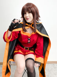 Rule 34 | 1girl, absurdres, arm support, asymmetrical legwear, belt, black cape, black gloves, black socks, blunt bangs, breasts, brown hair, cape, carpet, chair, cosplay, cosplay photo, dress, feet out of frame, fingerless gloves, gloves, highres, kneehighs, kono subarashii sekai ni shukufuku wo!, lips, long sleeves, looking at viewer, medium hair, megumin, megumin (cosplay), mismatched legwear, mole, mole on breast, parted lips, photo (medium), pointing, red dress, red eyes, sidelocks, single kneehigh, single sock, sitting, smile, socks, stelarhoshi, wall
