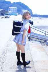 bag beach blue_eyes brown_hair cosplay cosplay_photo eye_contact from_behind loafers looking_at_another looking_at_viewer love_live! love_live!_sunshine!! outdoors photo_(medium) school_bag school_uniform serafuku shoes short_hair thighs uranohoshi_school_uniform watanabe_you