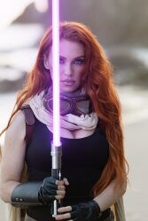 1girl black_gloves blue_eyes blurry blurry_background cosplay cosplay_photo depth_of_field energy_sword fingerless_gloves gloves goggles goggles_around_neck graciecosplay highres holding holding_sword holding_weapon lightsaber long_hair looking_at_viewer mara_jade may_the_4th orange_hair photo_(medium) purple_lightsaber solo star_wars sword upper_body weapon