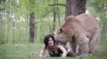 1girl animal animated bear black_hair blush breasts cosplay costume downblouse forest grass highres lara_croft large_breasts long_hair looking_at_viewer looking_back lying nature on_stomach outdoors photo_(medium) tomb_raider tomb_raider_(reboot) tree video