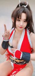1girl breasts brown_hair cleavage closed_mouth cosplay cosplay_photo fatal_fury female_focus highres large_breasts long_hair looking_at_viewer photo_(medium) ponytail real_life ririnacos shiranui_mai shiranui_mai_(cosplay) smile snk solo