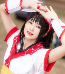 1girl ainu_clothes arms_up artist_name asian black_hair breasts brown_eyes cosplay fingerless_gloves gloves hair_ribbon highres japanese_(nationality) long_hair looking_at_viewer nakoruru parted_lips pink_lips ribbon samurai_spirits small_breasts smile snk solo teeth the_king_of_fighters the_king_of_fighters_xv