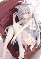 1girl absurdres ahoge animal_ears bare_shoulders barefoot blush breasts brown_eyes couch dress frilled_dress frills grey_hair hair_ornament hairclip halo highres holding knees_up long_hair looking_at_viewer nintendo_switch no_shoes on_couch original panties parted_lips pu_ht purple_halo simple_background sitting small_breasts solo thighhighs toes underwear white_background white_dress white_panties white_thighhighs