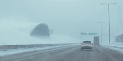 absurdres box_truck building car day from_behind highres highway lamppost motor_vehicle no_humans outdoors road road_sign sign simon_stalenhag snow sports_utility_vehicle swedish_machines traffic transmission_tower truck winter