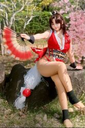 1girl breasts brown_hair cleavage cosplay cosplay_photo fatal_fury female_focus folding_fan hand_fan highres holding holding_fan large_breasts long_hair looking_at_viewer photo_(medium) ponytail real_life ririnacos shiranui_mai shiranui_mai_(cosplay) smile snk solo