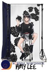 1girl :d amy_lee_(geeckek) backdrop bike_shorts_under_skirt black_boots black_choker black_eyes black_sweater boots bright_pupils character_name choker collarbone commentary earrings english_commentary floral_print full_body geeckek grey_hair grey_skirt hand_up highres jewelry long_hair long_sleeves looking_to_the_side mole mole_under_eye necklace on_stool open_mouth original photo_shoot pleated_skirt single_sleeve_past_wrist sitting skirt smile snail socks solo stool sweater swept_bangs tripod white_pupils white_socks