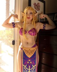1girl 2023 abs alternate_costume arm_tattoo armband arms_up bare_shoulders bikini blonde_hair blue_eyes bra braid clenched_hands collarbone commentary cosplay cosplay_photo cowboy_shot crown_braid day dresser english_commentary female_focus fingernails flexing highres indoors loincloth long_fingernails missbrisolo navel nintendo panties parted_bangs parted_lips patterned_clothing photo_(medium) picture_frame pointy_ears princess_zelda princess_zelda_(cosplay) purple_bikini purple_bra purple_panties real_life red_lips sideways_glance solo stomach straight-on sunlight swimsuit tattoo the_legend_of_zelda the_legend_of_zelda:_breath_of_the_wild thick_lips thick_thighs thighs toned toned_female triforce_print underwear wrist_tattoo
