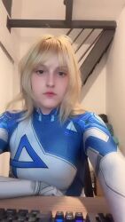1girl animated arms_up ass blonde_hair blue_bodysuit bodysuit brazilian_(nationality) breasts cosplay curvy fantastic_four hat highres indoors long_hair looking_at_viewer marvel marvel_rivals memepantazis photo_(medium) real_life sitting smile stretching sue_storm sue_storm_(cosplay) tagme two-tone_bodysuit video white_background