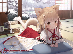 1girl :3 alcohol animal_ears bell blonde_hair blush brown_eyes choko_(cup) closed_mouth commentary_request cup day dog_ears dog_girl dog_tail eyelashes full_body hakama japanese_clothes jingle_bell leg_up long_hair long_sleeves looking_at_viewer lying miko on_bed on_stomach original pillow pot red_hakama rope sake shimenawa sidelocks snowing socks solo tail tatami tokuno_yuika tree winter