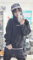 1girl absurdres baseball_cap black_hair black_hoodie black_pants cellphone hat highres hood hoodie indoors looking_at_phone mirror mirror_selfie pants phone photo_(medium) real_life room selfie short_hair smartphone standing ushijima_iiniku