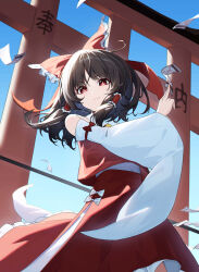 1girl absurdres ascot between_fingers blue_sky bow brown_hair chinese_commentary closed_mouth commentary_request day detached_sleeves frilled_bow frilled_hair_tubes frills gohei hair_bow hair_tubes hakurei_reimu highres holding holding_gohei jiangchuan_ling_yu_nai long_hair looking_at_viewer ofuda ofuda_between_fingers outdoors red_bow red_eyes red_skirt skirt skirt_set sky solo torii touhou yellow_ascot