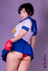 1girl artist_name ass blue_sailor_collar blue_skirt brown_eyes brown_hair capcom cosplay cosplay_photo female_focus fingerless_gloves gloves headband kasugano_sakura kasugano_sakura_(cosplay) kitty-honey looking_at_viewer looking_back matching_hair/eyes panties photo_(medium) real_life red_gloves red_panties sailor_collar school_uniform serafuku short_sleeves skirt solo street_fighter street_fighter_zero_(series) underwear watermark white_headband
