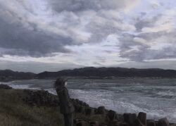 1girl absurdres akebonobashi_(artist) black_hair cloud cloudy_sky commentary_request dated_commentary from_behind highres hood hood_down lake landscape medium_hair mountain mountainous_horizon ocean original outdoors rock scenery shore sky solo standing water waves wide_shot