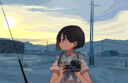 1girl black_hair blue_sky building camera closed_mouth cloud day field hands_up holding holding_camera looking_to_the_side mountainous_horizon original outdoors power_lines profile sailor_collar school_uniform serafuku shirt short_hair short_sleeves sky smile solo takaichi_(tkch) upper_body utility_pole white_shirt