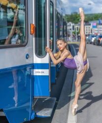 1girl ballerina ballet_slippers blue_sky blurry blurry_background car caterina_capacci leotard lipstick makeup motor_vehicle photo_(medium) purple_leotard see-through_clothes see-through_skirt skirt sky split standing standing_on_one_leg tram