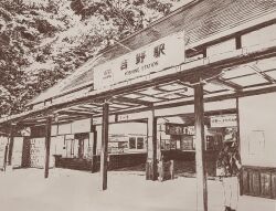 1boy architecture backpack bag ballpoint_pen_(medium) building commentary_request crosshatching east_asian_architecture english_text from_outside hat hatching_(texture) highres japan monochrome original outdoors pen_(medium) place_name real_world_location rural scenery sepia standing traditional_media train_station user_nnxt5288 wide_shot