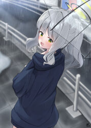 1girl :d black_halo blue_archive blue_hoodie blunt_bangs blush commentary_request from_above from_behind ganba_artworks green_eyes green_halo grey_hair hair_intakes halo hare_(blue_archive) highres hood hood_down hoodie long_hair long_sleeves looking_at_viewer looking_back open_mouth outdoors ponytail rain sidelocks smile solo transparent transparent_umbrella turning_head umbrella
