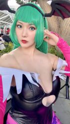 1girl asian breasts cleavage cosplay cosplay_photo costume darkstalkers green_eyes green_hair head_wings huge_breasts japanese_(nationality) large_breasts lipstick looking_at_viewer makeup medium_hair morrigan_aensland morrigan_aensland_(cosplay) outdoors photo_(medium) real_life selfie shibuya_kaho standing wings